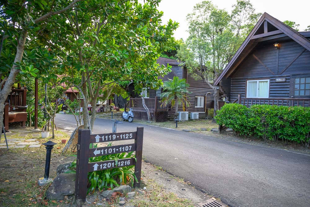 屏東小墾丁渡假村｜木屋、道路、樹木、指標、摩托車、草叢。