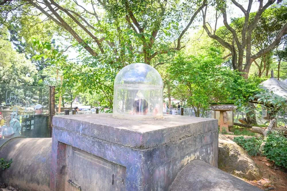 新竹六福村墓碑鎮｜石台、透明塑膠罩、樹、石燈籠、石塊、欄杆、圍牆。
