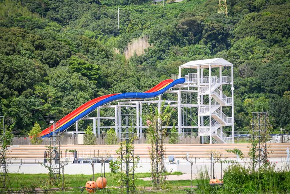 日本長崎-豪斯登堡米菲兔樂園｜彩色滑梯、白色高塔、樓梯、欄杆、森林、樹、草地、欄杆、雕像、柵欄。