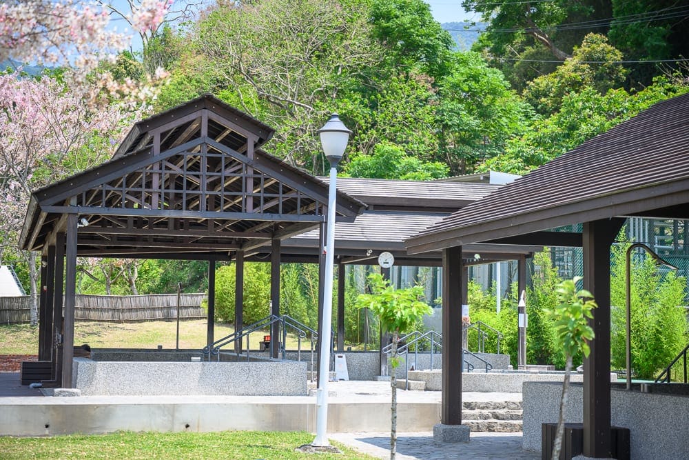 高雄寶來花賞溫泉公園花旗木｜戶外場所，木造建築，涼亭，草坪，樹木，花，燈柱，階梯，欄杆，木結構屋頂。