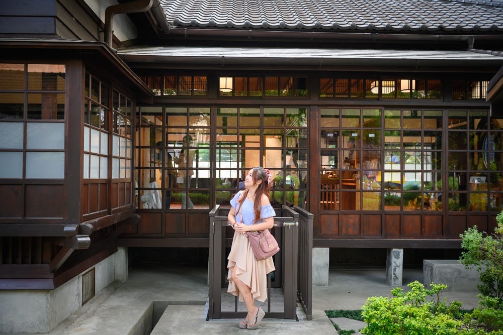 桃園大溪老街美食景點｜建築物外觀、木門、格子窗、和式屋頂，女子、側門、綠植。