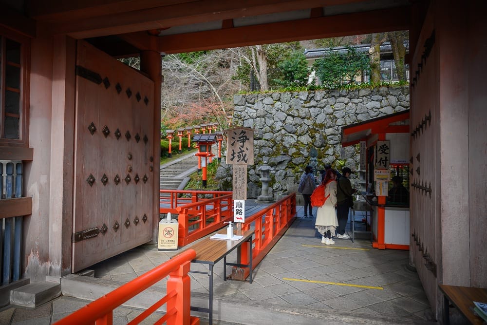 日本京都鞍馬寺修行之路｜寺廟、石牆、樓梯、木門、紅色欄杆、木桌，石燈籠與人們。