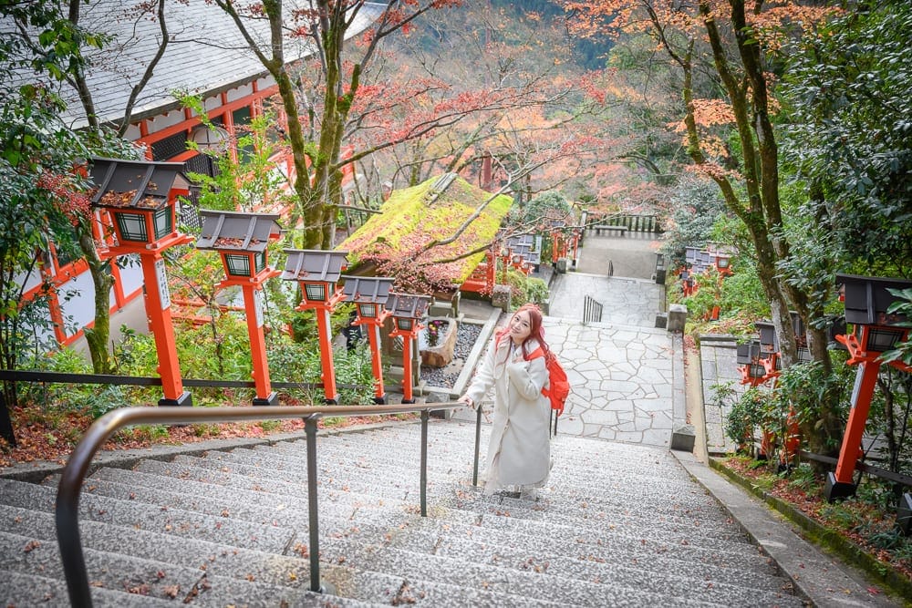 日本京都鞍馬寺修行之路｜石階、寺廟、紅色燈籠、樹、女穿白色和服，紅色背包，石路、欄杆。