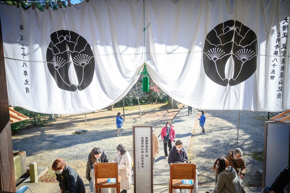 日本京都光明寺｜寺廟、庭院、石路、樹木，人群，白色布幔，黑色圖案，木椅，指示牌。