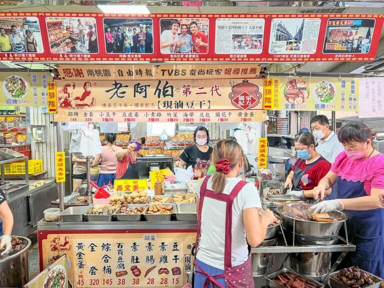 桃園大溪老街美食景點｜攤位、食物、顧客、員工、市場、料理。畫面中可見顧客正在點餐，員工正在忙碌地準備食物。