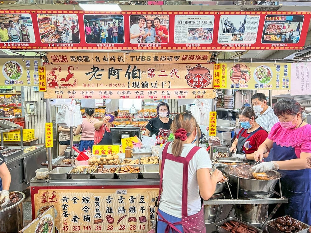 桃園大溪老街美食景點｜攤位、食物、顧客、員工、市場、料理。畫面中可見顧客正在點餐，員工正在忙碌地準備食物。