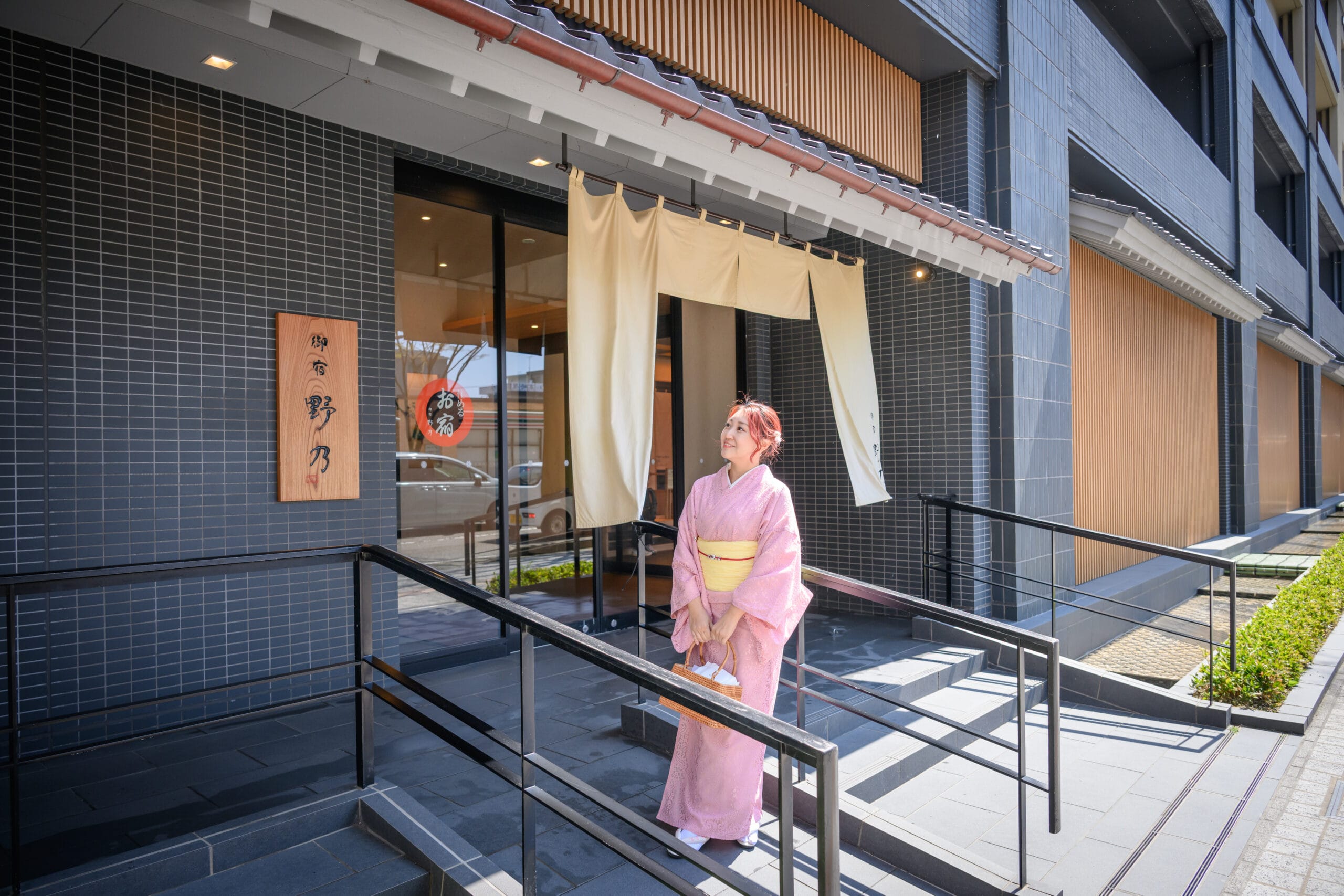 金澤御宿野乃飯店暖簾與木製招牌外觀，旅客著和服