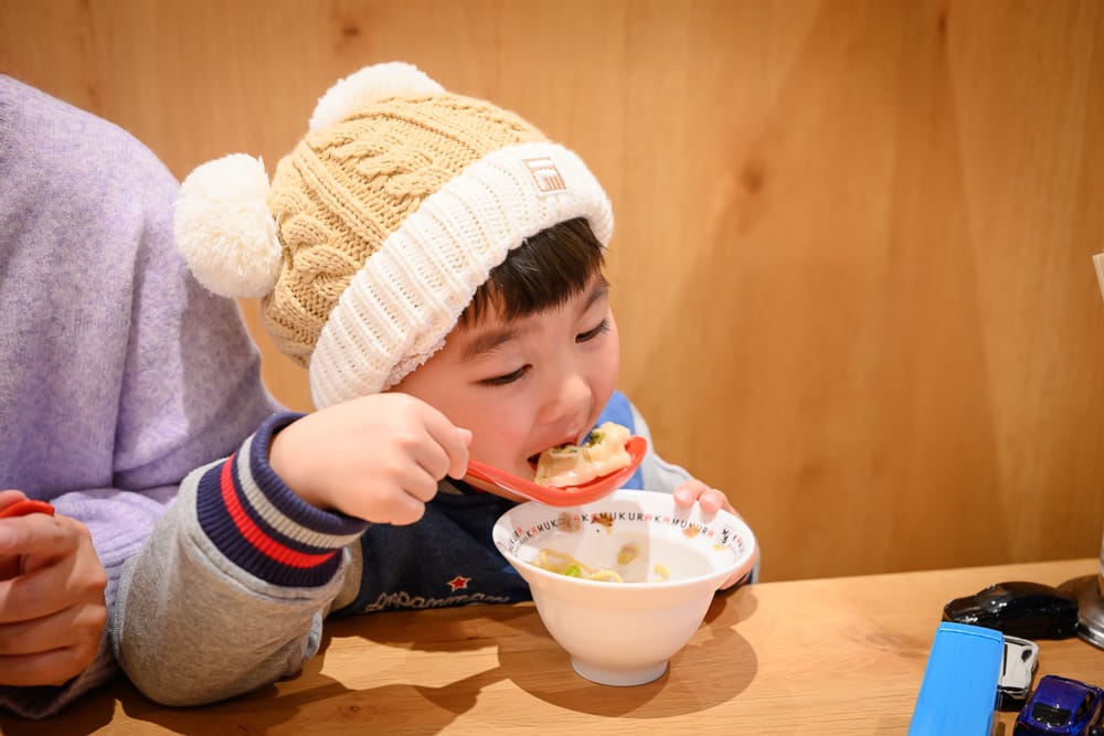 小孩在神座用湯匙吃煎餃