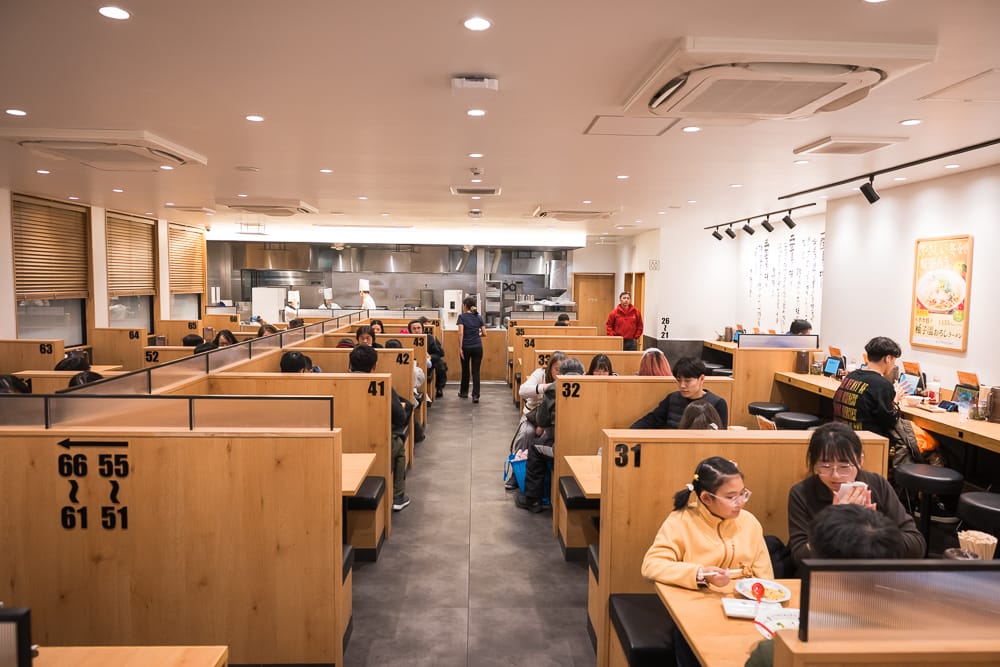 神座拉麵店內獨立木質卡座與開放式廚房用餐環境