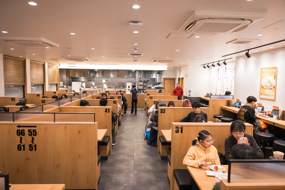 神座拉麵店內獨立木質卡座與開放式廚房用餐環境