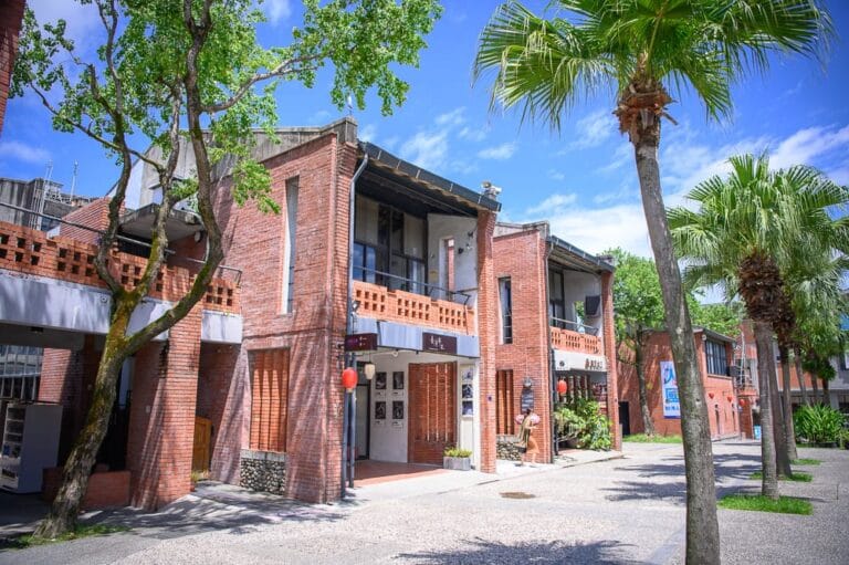 宜蘭傳藝文化園區｜紅磚建築群，街道，椰子樹，樹木，藍天，窗戶，招牌，紅色燈籠，戶外廣場。