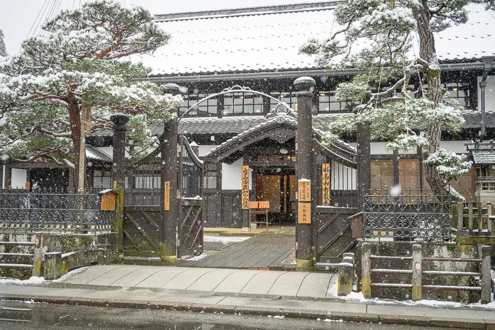 日本岐阜高山三町老街完整攻略|江戶建築群與飛驒牛小吃 8 日本高山-高山老街散冊|日本傳統建築,雪景,屋頂,松樹,大門,街道,飄雪,靜謐。