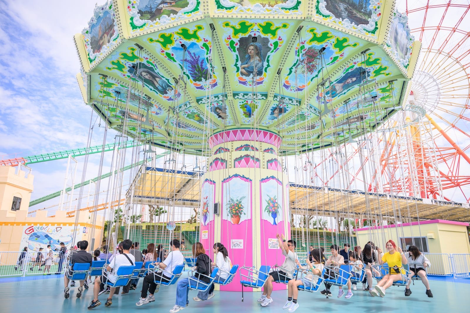 日本熊本-格林主題樂園｜遊樂園、旋轉咖啡杯、遊客、摩天輪、遊樂設施、建築物、藍天白雲。