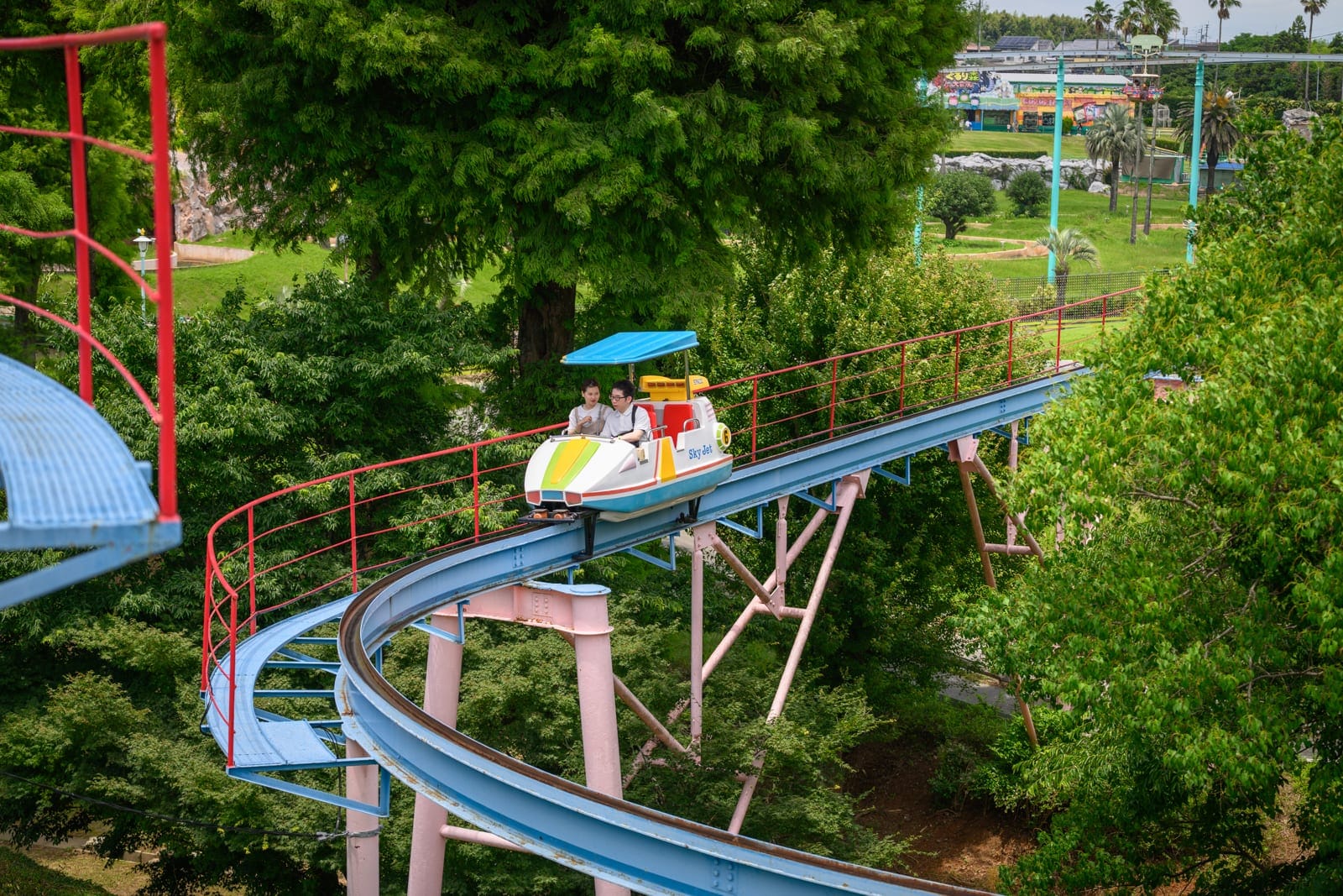 日本熊本-格林主題樂園｜遊樂園、軌道、樹林、遊樂設施、過山車、遊客。