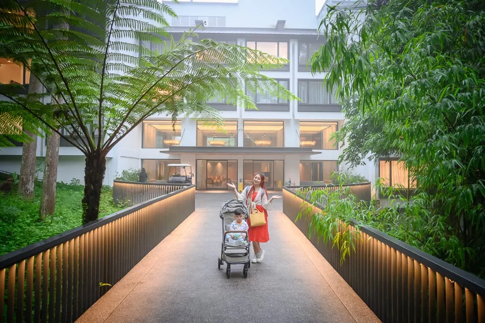 南投溪頭福華渡假飯店完整攻略|漢光樓住宿體驗與夜間生態導覽 12 南投溪頭福華飯店|橋、飯店、女子、推車、小孩、綠樹、燈光。女子推著嬰兒車站在飯店外面的發光步道上,兩側有茂密的綠樹與大