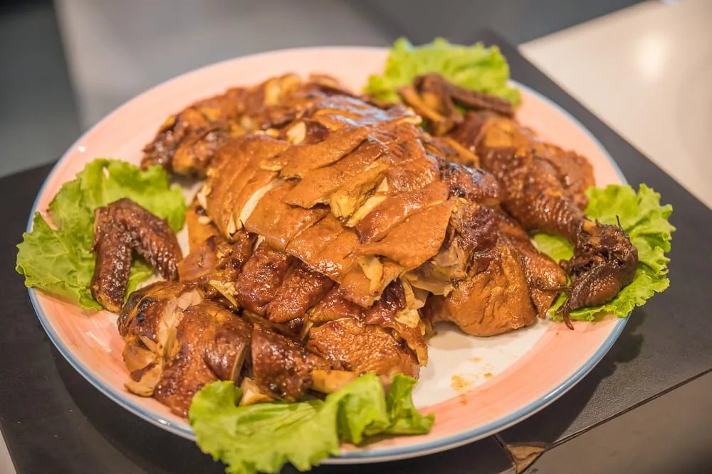 台東日暉渡假村｜料理，盤子，切片雞肉，生菜，室內。圓盤上擺放著切好的醬油色雞肉，周圍以生菜點綴。