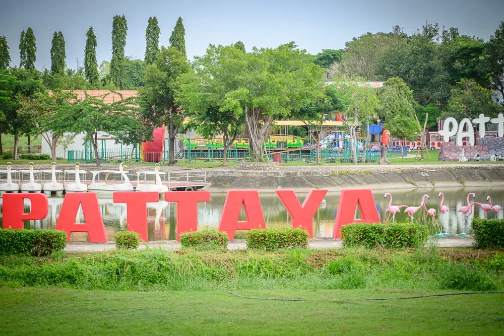泰國芭達雅GREAT&GRAND Sweet Destination｜戶外遊樂場景，紅色英文字母裝置藝術「PATTAYA」，水池，白色天鵝造型腳踏船，綠樹，草皮，粉紅鶴雕
