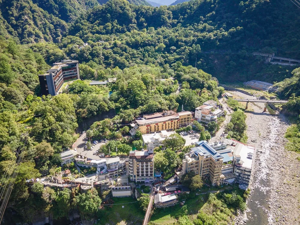 台中谷關統一渡假村｜群山，溪流，橋，飯店建築，樹林，山谷，俯瞰視角，道路，車輛，綠意植被，山坡聚落