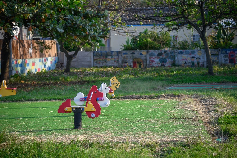 雲林麥寮國小積木公園｜綠地，搖馬遊具，樹木，彩繪矮牆，戶外廣場。人工草皮上設置數座色彩鮮豔的動物造型彈簧搖馬，後方為綠樹與