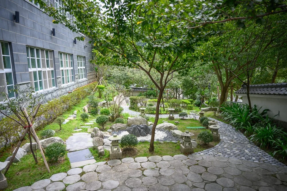 台中谷關統一渡假村｜庭園，石燈籠，步道，綠樹，灰磚牆，草地，圓形石板，窗戶