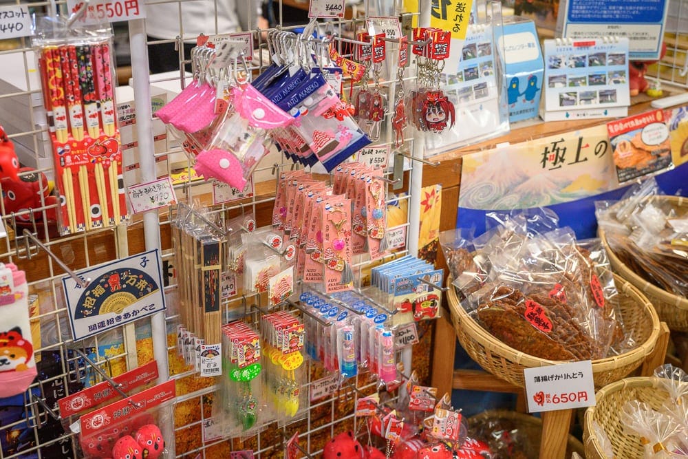 日本福島-吉利蛋公園｜商店、伴手禮、吊飾、竹籃、商品架、零食。商品架上掛滿粉紅小包、筷子與吊飾，右側木質竹籃內裝著袋裝零食