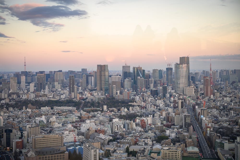 日本東京澀谷 SKY 觀景台完整攻略|360度夜景與購票實用指南 7 日本東京澀谷SKY觀景台|高樓大廈、市景、天空、雲朵、道路、遠山,黃昏夕陽光線映照密集錯落的建築群,遠方電塔與高塔聳立在地平線