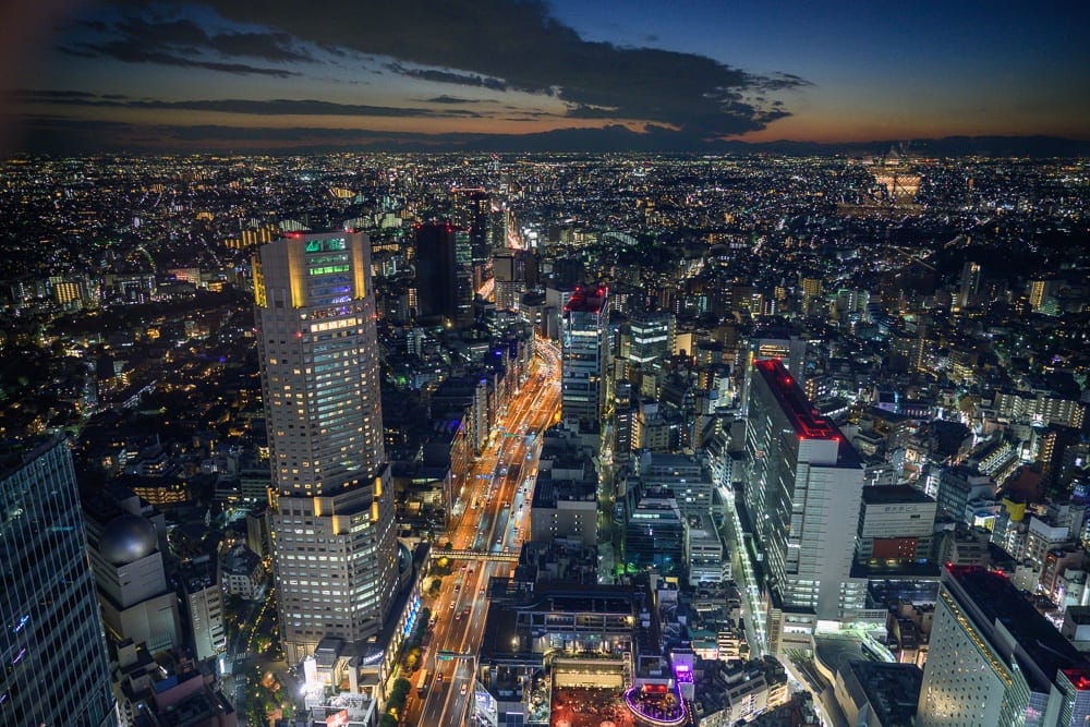 日本東京澀谷 SKY 觀景台完整攻略|360度夜景與購票實用指南 13 日本東京澀谷SKY觀景台|高樓大廈、街道、車流、燈光、城市夜景,黃昏藍色天際與綿延燈火交織,車燈軌跡劃過垂直的主幹道,遠方地平