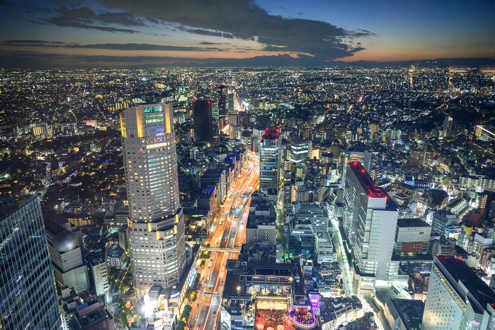 日本東京澀谷 SKY 觀景台完整攻略|360度夜景與購票實用指南 11 日本東京澀谷SKY觀景台|高樓大廈、街道、車流、城市夜景、遠山,暮色天空下方密布著發光的建築與縱橫道路,遠處地平線微亮。