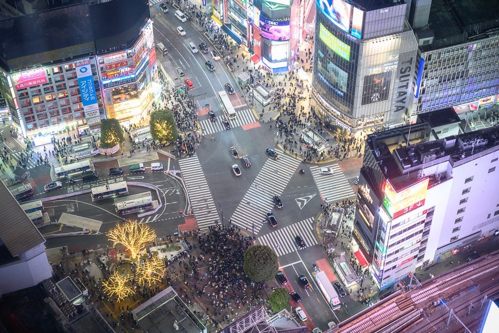 日本東京澀谷 SKY 觀景台完整攻略|360度夜景與購票實用指南 12 日本東京澀谷SKY觀景台|高空俯瞰都會十字路口,街道、車輛、行人、斑馬線、大樓、招牌。夜間燈光照亮密集的建築外牆與廣告螢幕,人