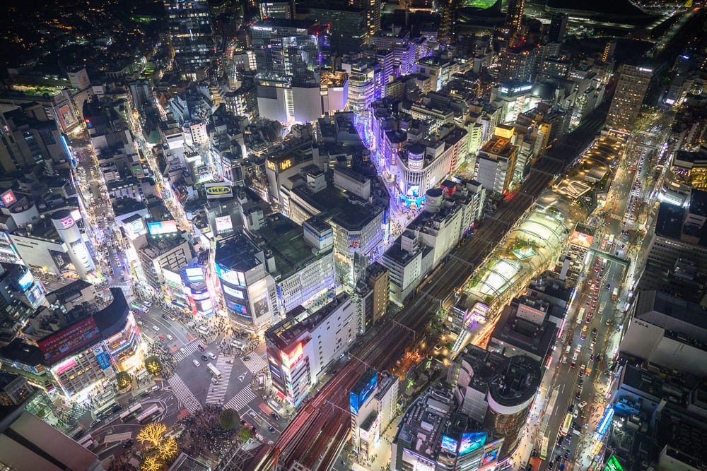 日本東京澀谷 SKY 觀景台完整攻略|360度夜景與購票實用指南 10 日本東京澀谷SKY觀景台|高空俯瞰夜間城市,街道、建築、霓虹燈招牌、十字路口、鐵軌,密集的商業區燈火通明,車流與行人交織。