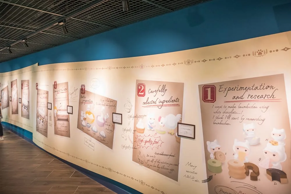 日本札幌-白色戀人觀光工廠｜室內，大型壁面展板，編號插畫，英文說明，黑色網格天花板，軌道射燈，木紋地板