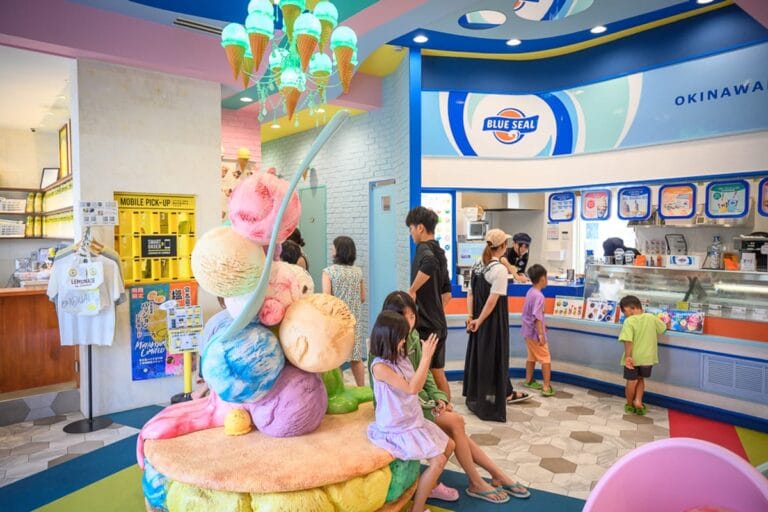 宮古島Blue seal｜室內，冰淇淋店，櫃台，巨型冰淇淋模型，吊燈，顧客。色彩繽紛的空間裡，顧客聚集在櫃檯前點餐，正中央設有