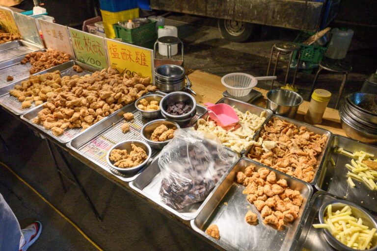 彰化田尾公路花園夜市｜夜市攤位，料理，炸物，金黃薯條，招牌，鐵盤，金屬碗，塑膠袋裝食材，夜市，金黃色調，油炸食物，金屬夾具