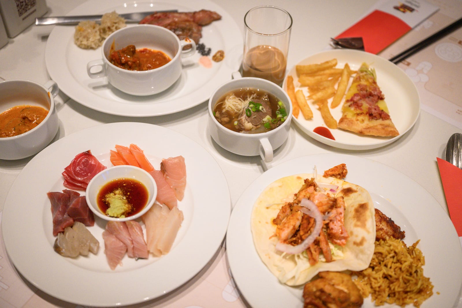 宜蘭凱渡廣場酒店｜料理、生魚片、披薩、薯條、牛肉麵、捲餅、湯品，白色桌面擺放多盤餐點、沾醬與玻璃杯。