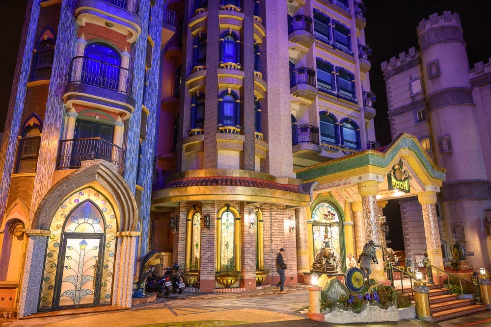 花蓮七星潭水上明月海景渡假旅店 Hotelmoon 完整攻略|歐式城堡建築與住宿體驗 6 花蓮水上明月海景旅店|城堡、圓柱、陽台、雕像、階梯,夜晚戶外燈光照明,建築外牆帶有藍色與金色裝飾,門面嵌有彩色玻璃,柱廊前