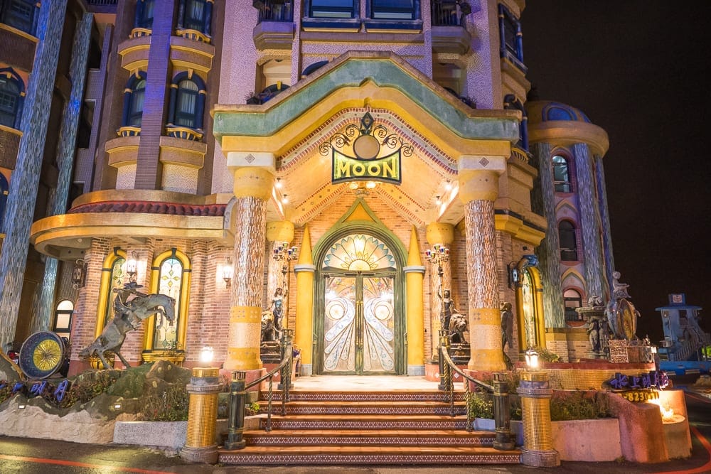 花蓮七星潭水上明月海景渡假旅店 Hotelmoon 完整攻略|歐式城堡建築與住宿體驗 13 花蓮水上明月海景旅店|城堡、石柱、雕像、階梯、招牌,夜間燈光照亮歐式建築門面,拱形玻璃雙扇門,外牆磚石紋理與圓拱窗戶,入口