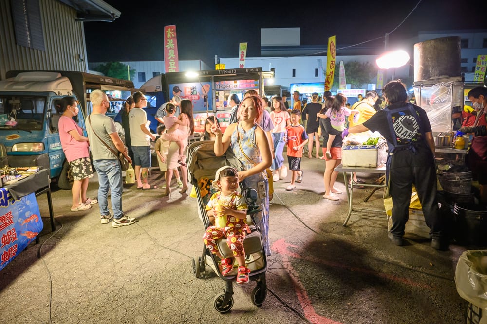 彰化秀水禮拜六夜市｜夜市、推車、攤販、人群、推車、幼童、招牌、路面，夜間戶外市集聚集多位攤商與步行民眾，孩童坐於推車中，