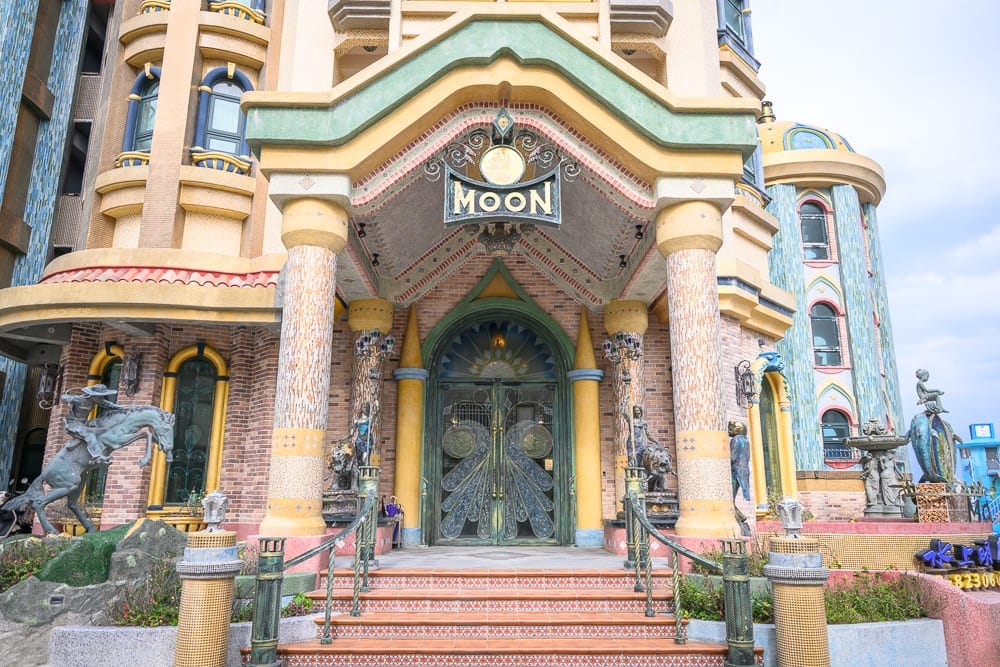花蓮七星潭水上明月海景渡假旅店 Hotelmoon 完整攻略|歐式城堡建築與住宿體驗 11 花蓮水上明月海景旅店|城堡,大門,柱子,雕像,階梯。歐式奇幻風格建築,正面掛著「MOON」招牌,兩側有石雕與拱形窗戶,陰天