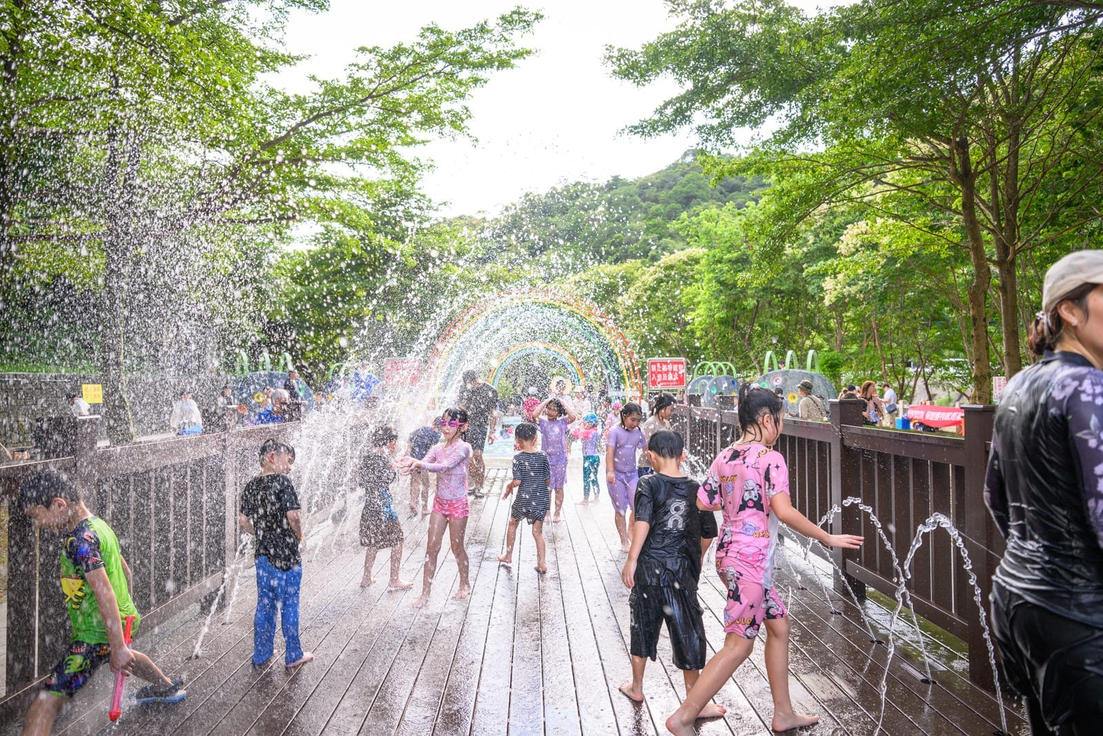 基隆暖暖親水公園完整指南|淺水戲水池與親子玩水設施解析 9 基隆暖暖親水公園|戶外公園噴水設施,木棧道,噴泉,彩虹水霧,綠樹,兒童戲水,夏日活動,大人小孩