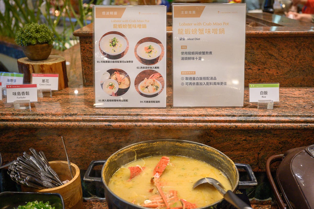新竹煙波大飯店 新竹湖濱館完整攻略|餐飲設施與親子體驗指南 1 新竹煙波湖濱館|料理,湯鍋,標示牌,餐具,大理石檯面。自助餐廳吧檯上擺放著龍蝦螃蟹味噌鍋,鍋內有蟹殼與黃色湯汁,後方