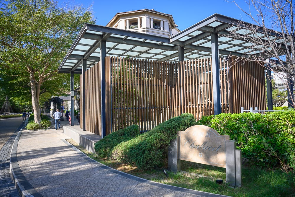 新竹煙波大飯店 新竹湖濱館完整攻略|餐飲設施與親子體驗指南 11 新竹煙波湖濱館|戶外、街道、木格柵建築、綠樹、行人步道,晴朗藍天下的建築結構,建築外圍設有金屬與玻璃屋頂,前方有低矮