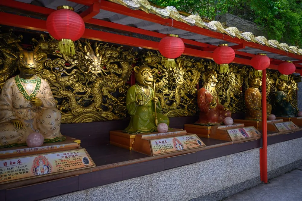 桃園威天宮｜寺廟，雕像，紅燈籠，金色浮雕。成排動物生肖造型神像端坐於台座上，身穿彩繪長袍，背後為華麗金龍木雕牆面