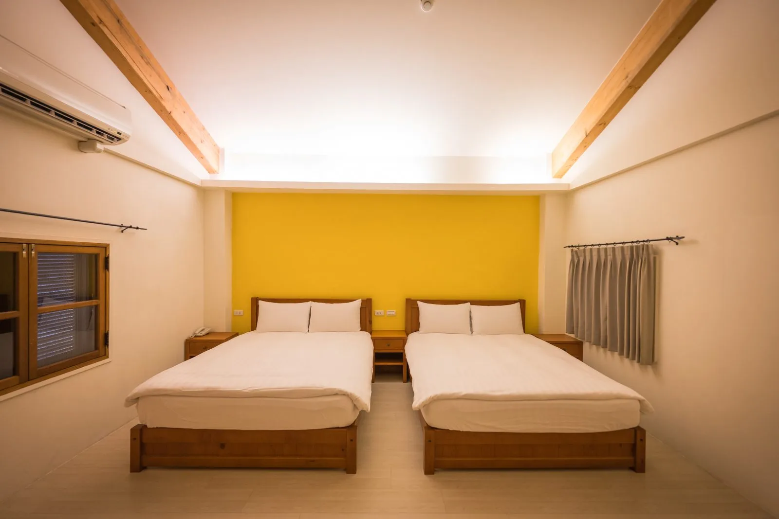 台中薰衣草森林住宿及園區｜香草House 客房、兩張單人床、黃色主牆、橫向木樑、木框窗、冷氣。兩張單人床並排靠牆，床頭為整面黃色主牆。