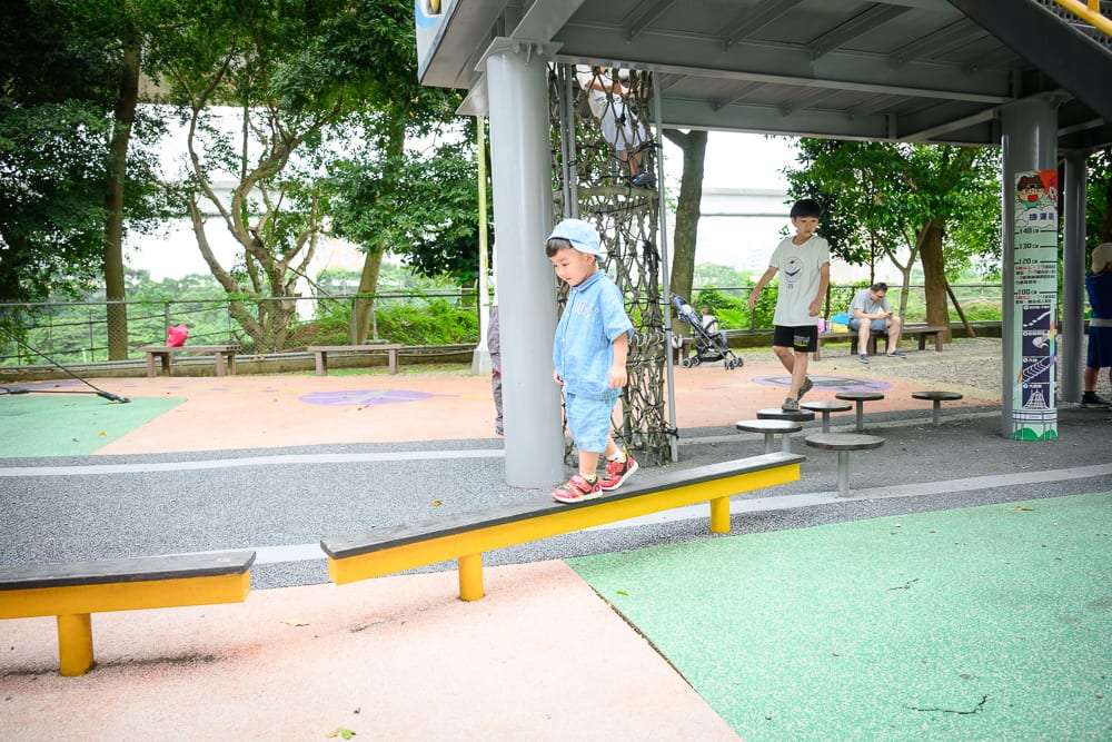 新北林口樂活公園｜兒童遊戲場，平衡木，塑膠地墊，金屬柱，繩網，樹木，男童。