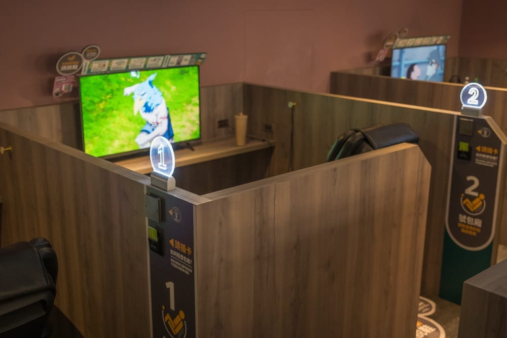 高雄 E7PLAY 三多館完整攻略|保齡球道、電子飛鏢與多元機台玩法解析 11 高雄E7play|室內,隔間,螢幕,電視,座椅,燈號,牆面。獨立木紋隔間包廂內部設置座位與顯示器,編號燈箱與螢幕畫面清