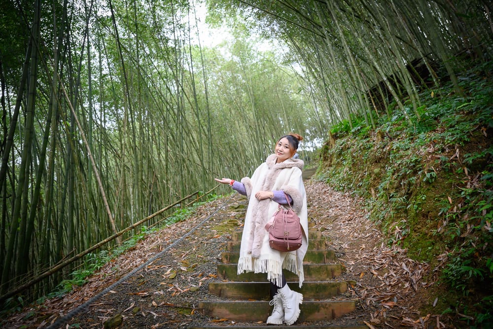 嘉義寒溪呢｜女性、竹林、階梯、披肩、後背包、小徑，身穿白色毛邊披肩與靴子的女子站在竹林間的戶外木階梯上，右手向旁
