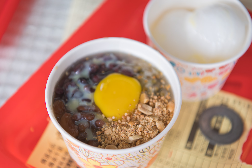 宜蘭建華冰店｜紅盤上的紙杯裝甜點，含紅豆、蛋黃與花生碎，旁有冰品。