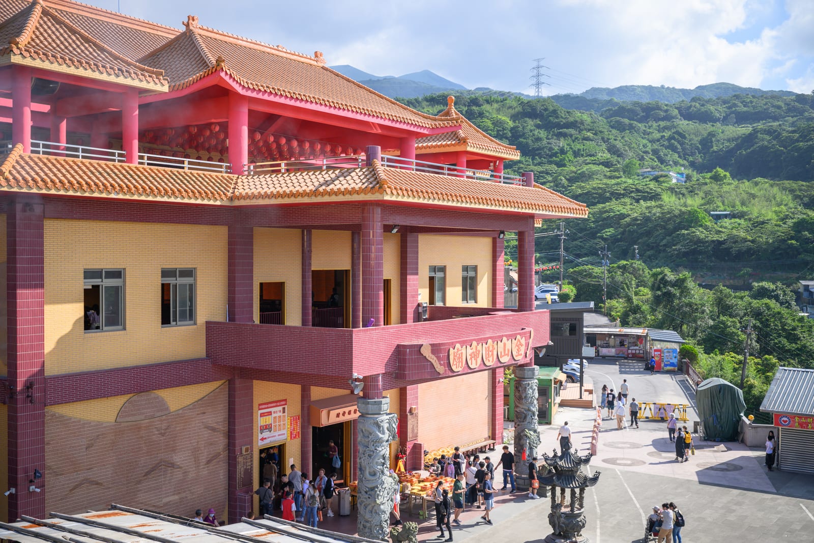 金山財神廟座落山林間,廟內挑高大廳以層疊金元寶祭壇與紅色圓柱為主要景觀,戶外廣場可俯瞰金山平原與海岸。文章涵蓋大廳神壇格局、錢進號周邊商品區、觀景露台視野,以及交通方式與造訪建議,幫助自由行旅客規劃行程。