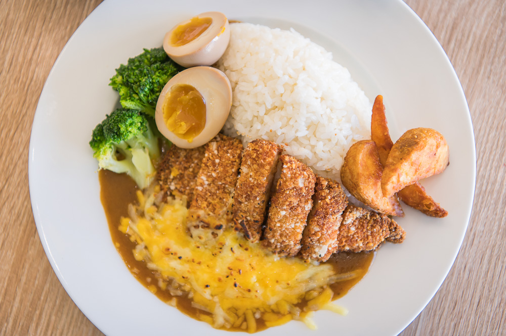 新北井號早午餐｜盤中盛裝炸豬排咖哩飯、溏心蛋、花椰菜與薯塊，置於木紋桌面。