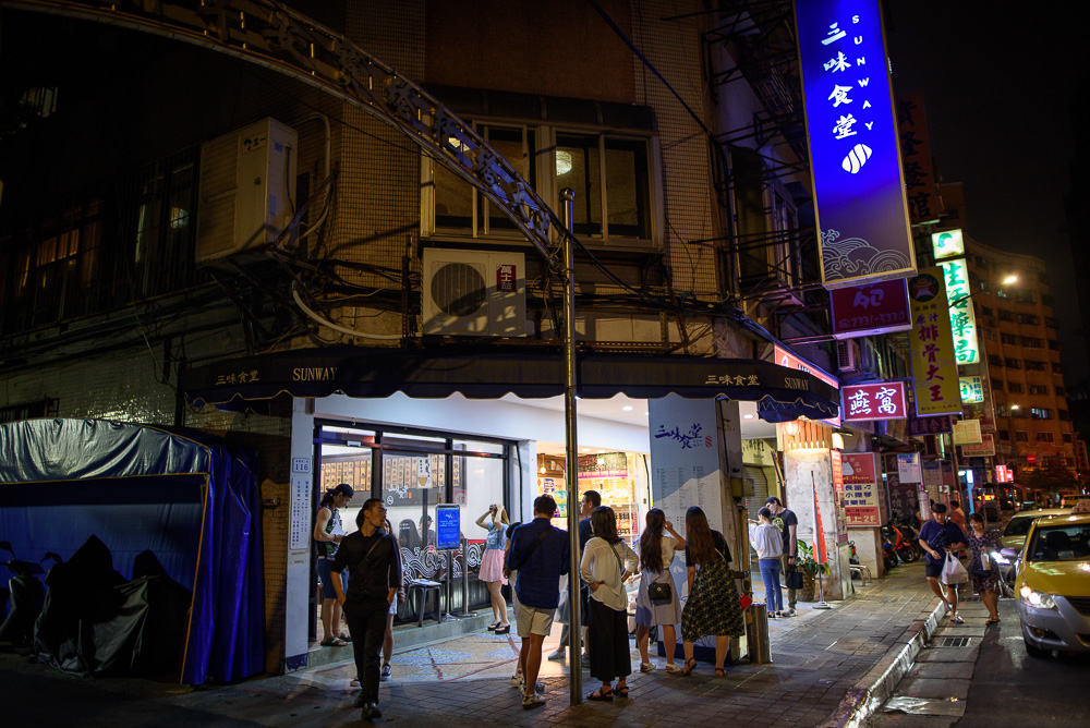 台北三味食堂｜台北夜間街頭，三味食堂餐廳門口，排隊人潮，招牌燈箱，計程車。